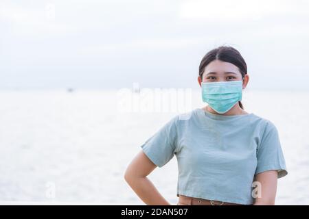 Asiatische Teenager-Frau trägt eine Gesichtsmaske im Freien mit Platz für Text. Stockfoto