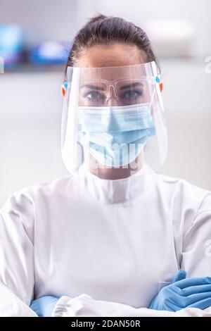Ärztin trägt Schutzkleidung wie Schild, Gesichtsmaske und Schutzhandschuhe. Stockfoto