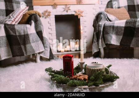 Eine Tasse heißen Kräutertee auf einem eisernen Tablett mit Christbaumzweigen, brennenden Kerzen, Zapfen, Keksen, Spielzeug. Weihnachten Hintergrund. Neujahr Stockfoto