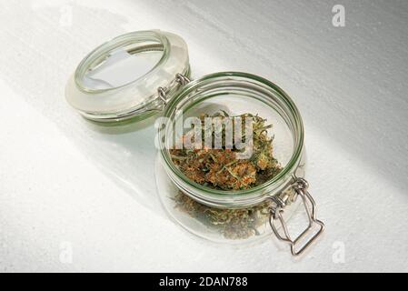 Getrocknete Knospen von Marihuana in einem offenen Glas auf Ein heller Hintergrund Stockfoto