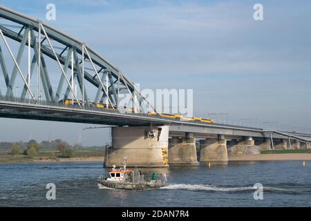 Niederländischer Personenzug, der eine blaue Brücke in Nijmegen, Gelderland passiert Stockfoto