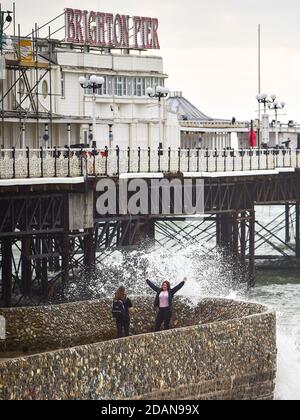 Brighton UK 14. November 2020 - Wellen krachen über der Strandpromenade von Brighton und Besucher können sich an einem windigen Tag an der Südküste entspannen : Credit Simon Dack / Alamy Live News Stockfoto