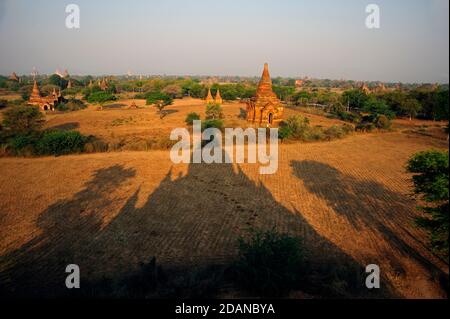 Der lange dunkle deutliche Tempelschatten erstreckt sich in Richtung der Tempel auf dem staubigen Bagan palin Bagan Myanmar Stockfoto