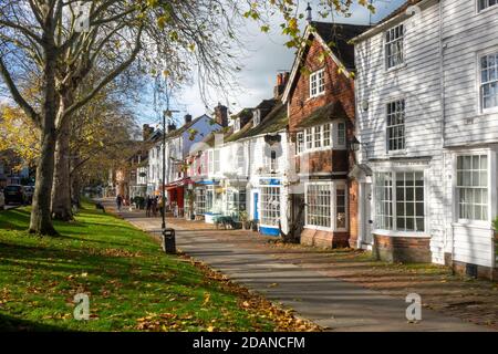 Tenterden, Leute in Cafés mit Tischen im Freien, an eleganten Geschäften auf dem malerischen breiten Bürgersteig der von Bäumen gesäumten High Street, Kent, Großbritannien Stockfoto