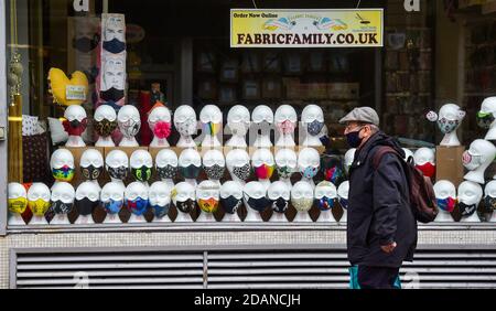 Brighton UK 14. November 2020 - EIN Mann, der eine Gesichtsbedeckung trägt, passiert ein geschlossenes Geschäft, das Masken in Brighton verkauft, da das Einkaufsviertel der Stadt aufgrund der neuesten Coronavirus COVID-19 Sperrbeschränkungen in England ruhig bleibt : Credit Simon Dack / Alamy Live News Stockfoto