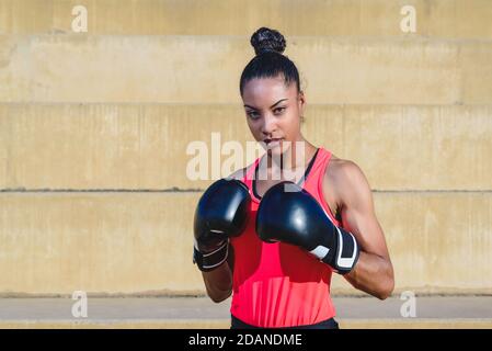 Horizontales Porträt einer attraktiven afrikanischen Frau in Sportkleidung Und Boxhandschuhe stehen in Verteidigungspose Stockfoto