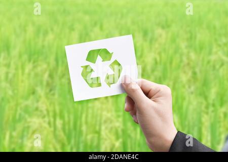 Hand halten weiße Papier-Karte mit Recycling-Logo auf grünem Natur-Hintergrund. Earth Day Konzept Stockfoto