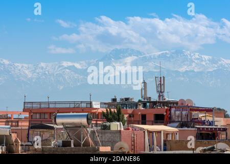 Gebäude der Stadt Marrakesch im Vordergrund, und das Atlasgebirge im Hintergrund. Kontraste der Stadt, Reisekonzept. Marrakesch, Mor Stockfoto