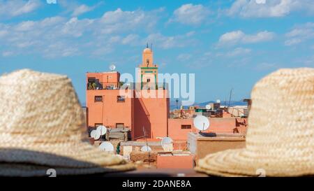 Typische bunte Gebäude der Medina von Marrakesch an einem sonnigen Tag mit einem blauen Himmel und einigen Wolken. Hüte aus Fokus im Vordergrund. Reisekonzept Stockfoto