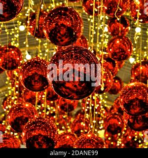 Glänzende rote weihnachtskugeln, die von goldenen Lichterketten aufgehängt werden Stockfoto
