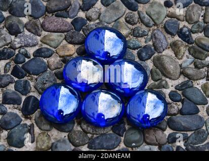 Kleines Dreieck aus irisierenden blauen Glasperlen auf einem steingestrichelten Steinhintergrund isoliert. Stockfoto