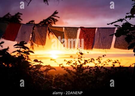 nepalesische Gebetsfahnen winken während des Sonnenuntergangs Stockfoto