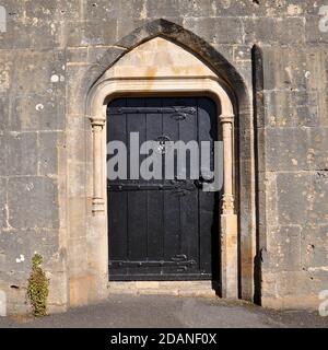 Schwarze hölzerne gotische Art gewölbte Tür in einer alten englischen Kirche. Stockfoto