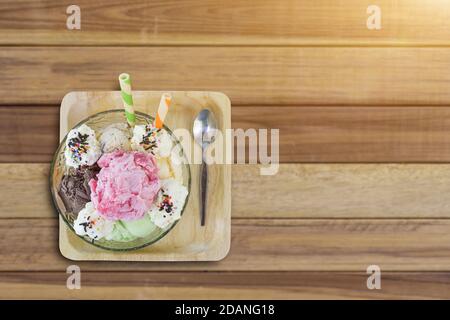 Schüssel mit Eisschaufeln in verschiedenen Farben und Geschmacksrichtungen auf Holz Hintergrund. Selektiver Fokus Stockfoto