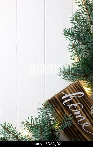 Startseite Schriftzug gebranntes Holz Zeichen und Weihnachtsbaum Äste auf weißer Holzfläche. Flach liegend, Kopierplatz. Vertikal Stockfoto