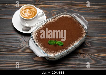 Traditionelle italienische Tiramisu Dessert in Glas Backform und Tasse Von frischem heißem Espresso-Kaffee auf Holzhintergrund Stockfoto