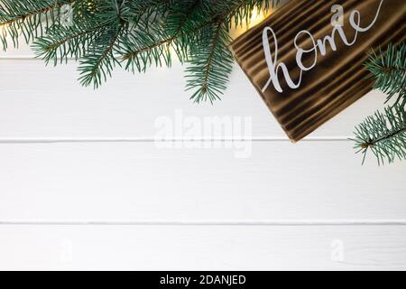 Startseite Schriftzug gebranntes Holz Zeichen und Weihnachtsbaum Äste auf weißer Holzfläche. Flach liegend, Kopierplatz. Stockfoto