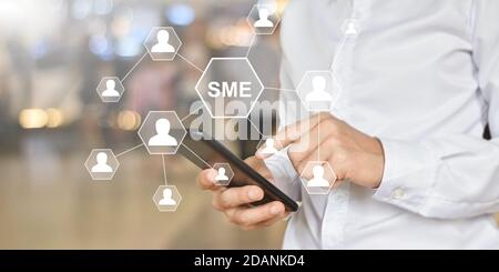 Mann Hand hält Smartphone mit Symbol Menschen auf dem virtuellen Bildschirm. Idee für KMU oder kleine und mittlere Unternehmen. Stockfoto