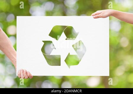 Hand halten Whiteboard mit Recycling-Logo auf grünem Natur-Hintergrund. Earth Day Konzept Stockfoto
