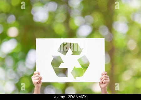 Hand halten Whiteboard mit Recycling-Logo auf grünem Natur-Hintergrund. Earth Day Konzept Stockfoto