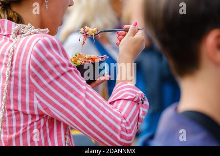Crop Frau essen Salat in der Menge Stockfoto