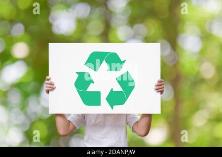 Mädchen Hand hält weißes Brett mit Recycling-Logo über grüne Natur Hintergrund. Earth Day Konzept Stockfoto