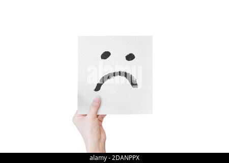 Hand hält weißes Papier mit Hand gezeichnet unglücklich Gesicht Emoticons isoliert auf weißem Hintergrund. Mit Clipping-Pfad. Stockfoto