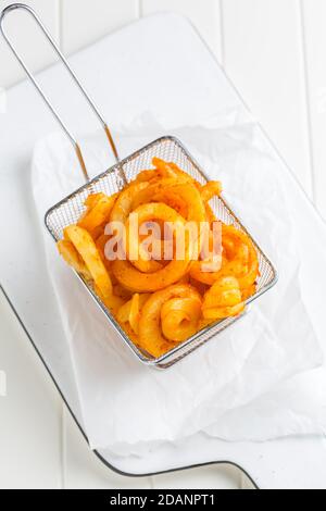 Würzige gewürzte lockige Pommes Frites. Bereit, auf weißem Hintergrund zu essen Stockfoto