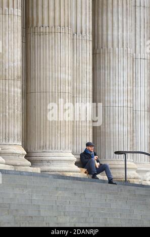 London, England, Großbritannien. Mann, der sein Mittagessen auf den Stufen der St. Paul's Cathedral isst, um die zweite COVID-Sperre zu heilen, November 2020. Stockfoto