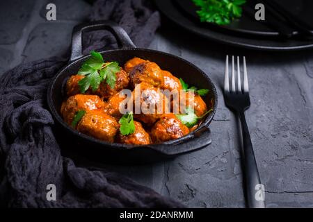 Fleischbällchen mit Tomatensauce in schwarzer Pfanne Stockfoto