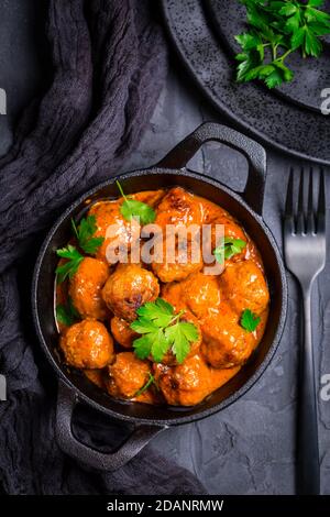 Fleischbällchen mit Tomatensauce in schwarzer Pfanne Stockfoto