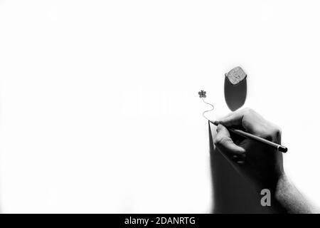 Ein minimalistisches abstraktes Schwarz-Weiß-Porträt einer Hand Einer Person, die eine wirbelnde Linie unter einer Zeichnung zeichnet Schmetterling mit einem Bleistift mit einem starken Stockfoto