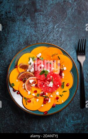 Gesunder Wintersalat - Persimmon Carpaccio Salat mit Granatapfel, Feta, rosa Grapefruit und Feigen Stockfoto