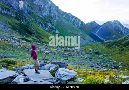 Junger Mann von der Seite mit Blick auf das Bergtal. Aibga Kamm, allein reisen, Trekking in den Bergen, Landschaft Stockfoto