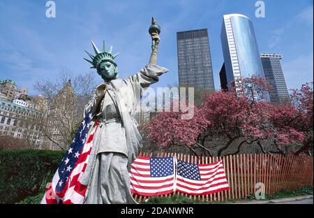 New York, USA-JULY 19,2018: Eine lebende Freiheitsstatue mit der amerikanischen Nationalflagge Pantomime posiert für Fotos (und Tipps) im Battery Park Stockfoto