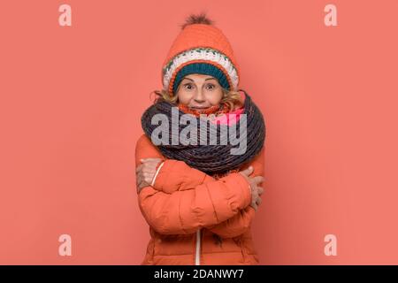 Reife eiskalte Frau trägt mehrere Schals und Hüte. Stockfoto