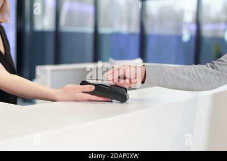 Junger Mann hält Smartphone über teminal von weiblichen Administrator gehalten Stockfoto