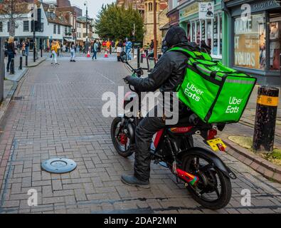 Uber isst Food Delivery Courier auf einem Elektrofahrrad im Stadtzentrum von Cambridge. Uber Isst Lebensmittel Lieferung Courier Elektroroller. Stockfoto