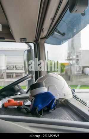 Persönliche Schutzausrüstung in der Kabine eines LKW, der gefährliche Güter transportiert, bestehend aus Helm, Schutzbrille, Gasmaske und Exp Stockfoto