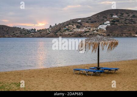 Strohschirm mit Sonnenliegen am Sandstrand von Chora auf der Insel iOS. Kykladen, Griechenland Stockfoto