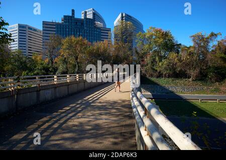 Eine Frau joggt auf dem Fußgängerweg über den George Washington parkway und blickt auf die Skyline von Rosslyn. In Rosslyn, Arlington, Virginia. Stockfoto