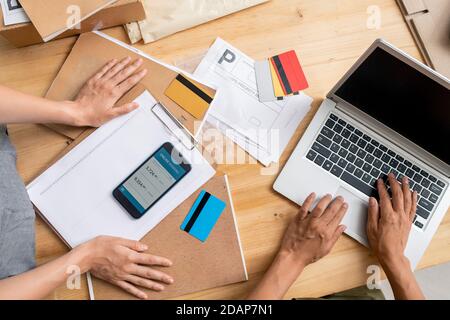 Hände von jungen Managern mit mobilen Gadgets beim Empfang online Zahlungen Stockfoto