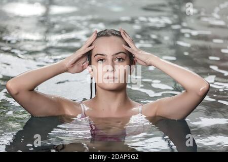 Schöne junge Frau mit reiner glatter Haut genießen Entspannung in Pool während des Spa-Verfahrens im Wellnesscenter Stockfoto