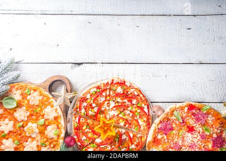 Weihnachtlich geschmückte Pizza. Set aus verschiedenen hausgemachten Pizza mit Weihnachtsdekoration - Cheesy Schneeflocken, Weihnachtsbaum Scheiben und Pepperoni Sterne, mit dez Stockfoto