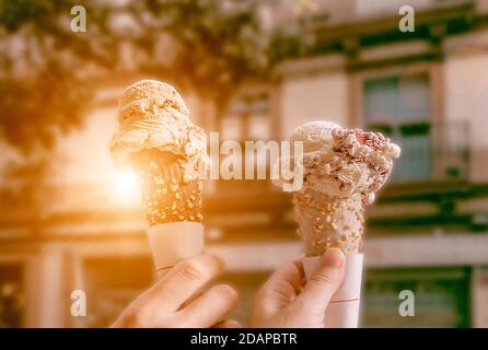Ein Paar hält Eisschaufeln in Zapfen mit Schokolade, Vanille und Erdbeere. Touristen in Europa an einem heißen Sommertag genießen Eiszapfen. Stockfoto