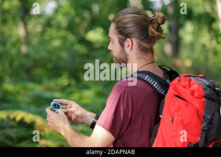 Mann mit Rucksack, der auf die Richtung auf dem Kompass schaut Stockfoto