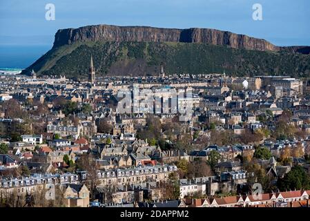 Wohnhäuser in Süd-Edinburgh mit Salisbury Crags im Hintergrund, aufgenommen aus Blackford Hill, Edinburgh, Schottland, Großbritannien. Stockfoto