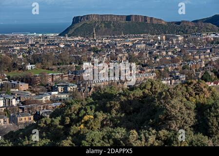 Wohnhäuser in Süd-Edinburgh mit Salisbury Crags im Hintergrund, aufgenommen aus Blackford Hill, Edinburgh, Schottland, Großbritannien. Stockfoto