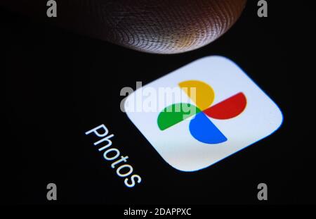 Stafford / Vereinigtes Königreich - November 12 2020: Google Fotos App und verschwommene Fingerspitze darüber bereit, den Bildschirm des Smartphones zu drücken. Stockfoto