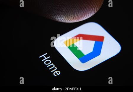 Stafford / Vereinigtes Königreich - November 12 2020: Google Home App und verschwommene Fingerspitze darüber bereit, den Bildschirm des Smartphones zu drücken. Stockfoto
